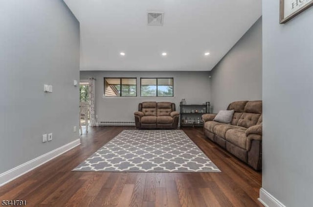 living area with dark wood finished floors, visible vents, a baseboard heating unit, and baseboards