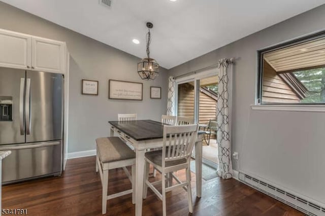 dining room featuring a baseboard heating unit, plenty of natural light, dark wood-type flooring, and a chandelier