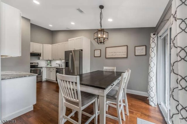 dining space featuring visible vents, baseboards, dark wood finished floors, lofted ceiling, and an inviting chandelier