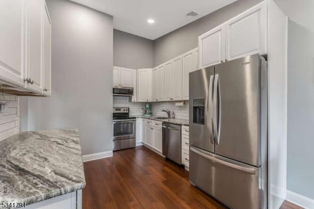 kitchen featuring a sink, light stone countertops, backsplash, and appliances with stainless steel finishes