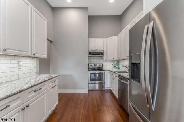 kitchen featuring a sink, dark wood-style floors, stainless steel appliances, white cabinets, and light stone countertops