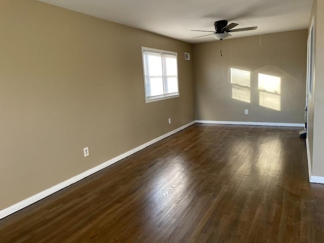 spare room featuring ceiling fan, baseboards, and dark wood finished floors