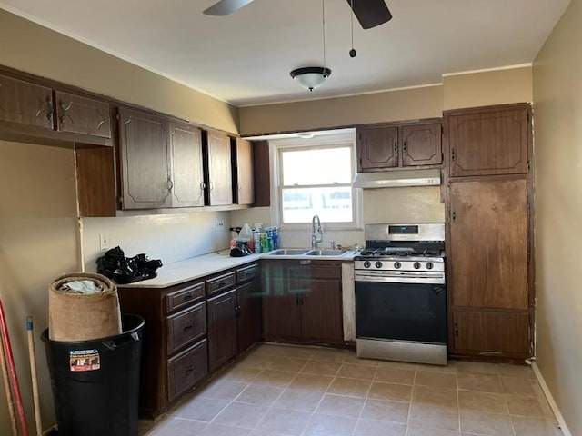 kitchen featuring ceiling fan, stainless steel gas range, light countertops, under cabinet range hood, and a sink