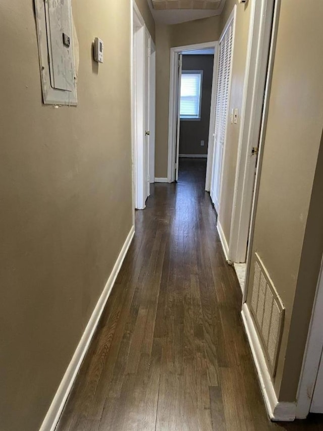 corridor with electric panel, dark wood finished floors, visible vents, and baseboards