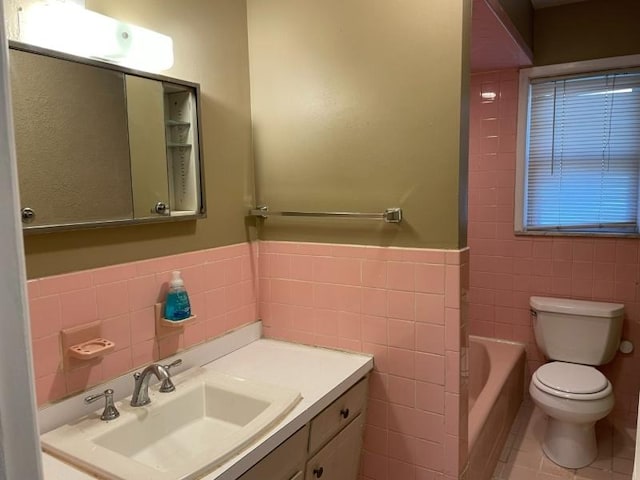 bathroom with tile walls, toilet, a bathing tub, vanity, and tile patterned flooring