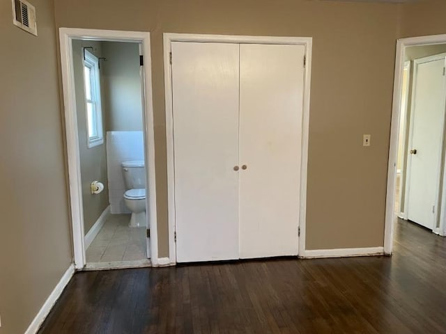 unfurnished bedroom with baseboards, a closet, visible vents, and wood finished floors