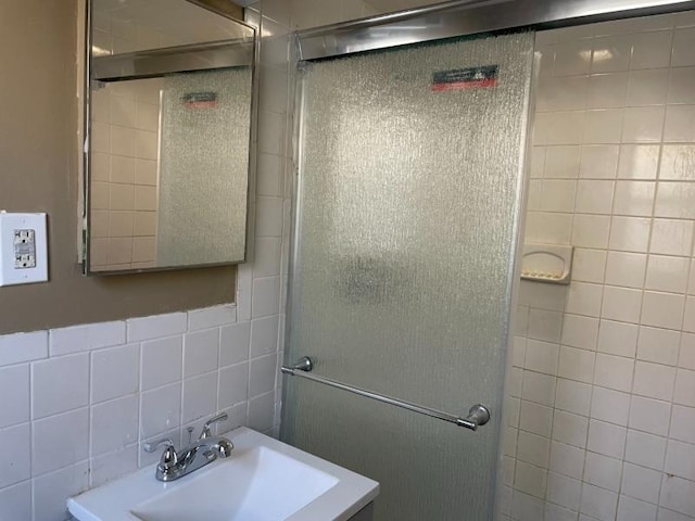 full bathroom featuring backsplash, a shower with door, a sink, and tile walls