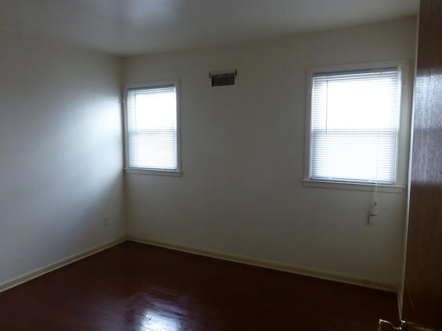 empty room featuring baseboards, visible vents, and wood finished floors