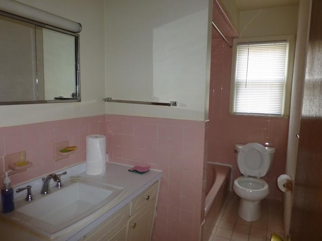 full bathroom featuring a wainscoted wall, tile walls, toilet, vanity, and tile patterned flooring