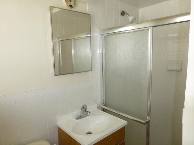 bathroom featuring tile walls, tiled shower, and vanity