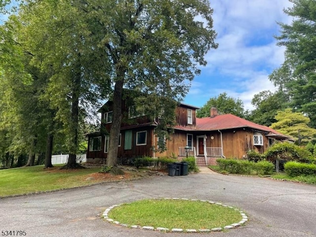 view of front facade featuring aphalt driveway and a chimney