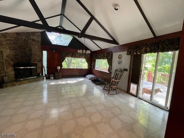 unfurnished living room featuring high vaulted ceiling, a stone fireplace, a skylight, and beam ceiling