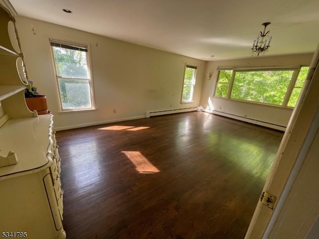 unfurnished room featuring a baseboard heating unit, dark wood-style flooring, a notable chandelier, and baseboards