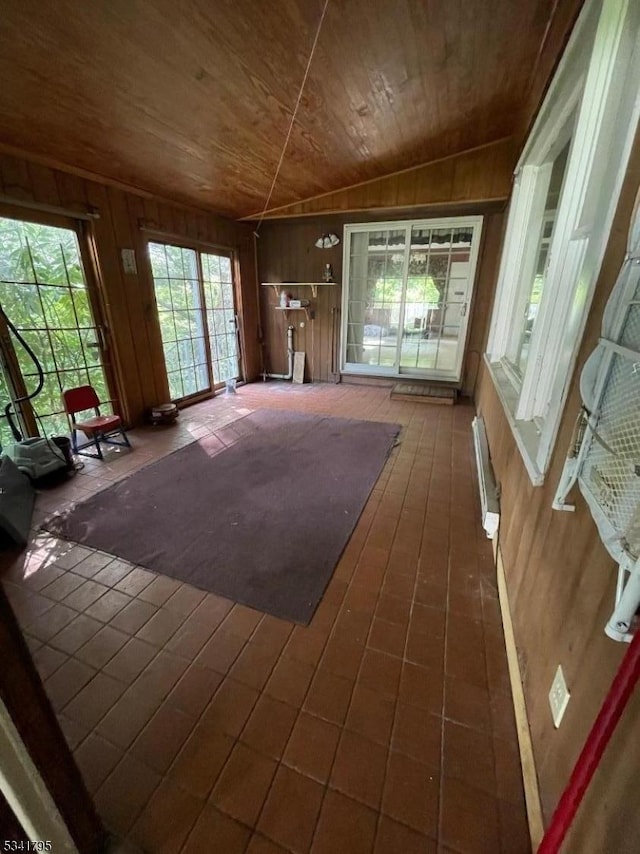 unfurnished living room with lofted ceiling, wood ceiling, and wooden walls