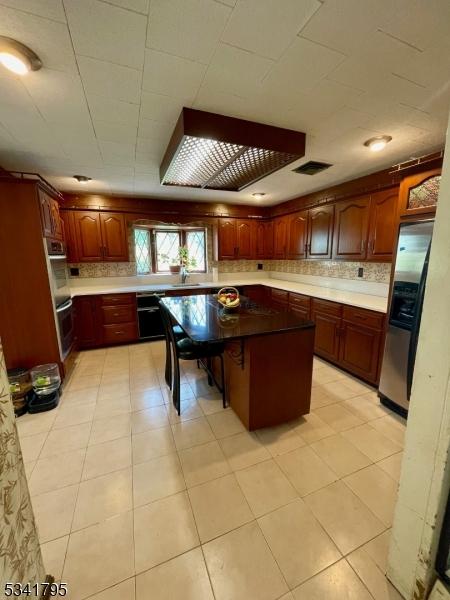 kitchen with appliances with stainless steel finishes, a sink, a center island, and decorative backsplash