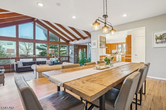 dining room with light wood-style floors, baseboards, a wealth of natural light, and beamed ceiling