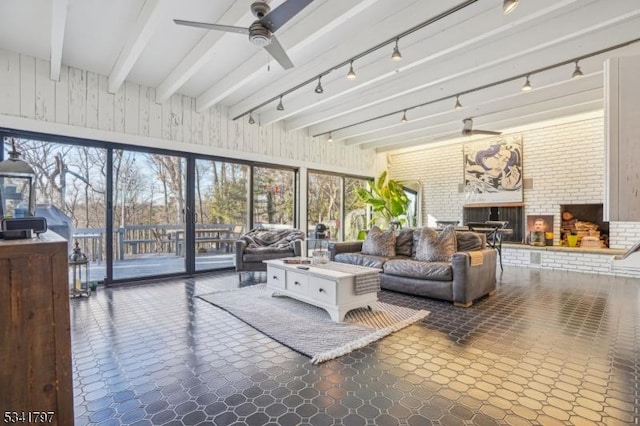 sunroom featuring beamed ceiling, a fireplace, and a ceiling fan