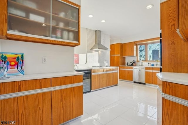 kitchen featuring dishwasher, light countertops, wall chimney range hood, and decorative backsplash