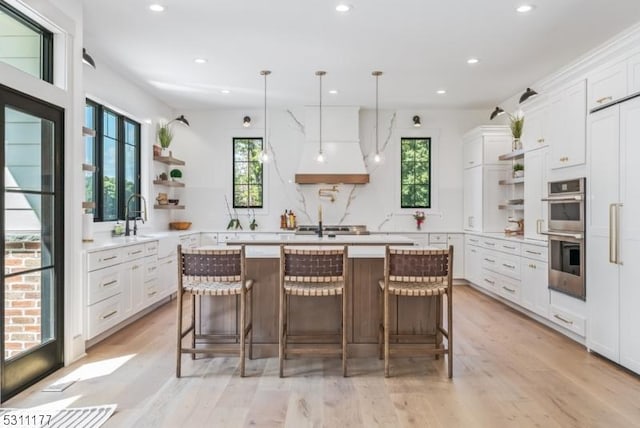 kitchen with stainless steel double oven, premium range hood, a kitchen island, and open shelves