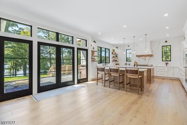 kitchen featuring white cabinets, light wood-style flooring, a breakfast bar, light countertops, and recessed lighting