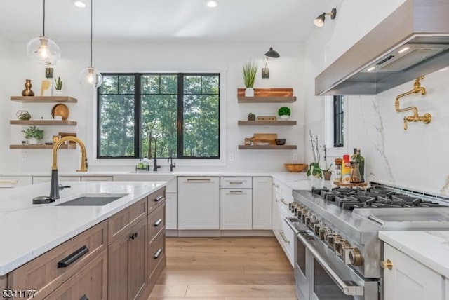 kitchen with double oven range, custom range hood, open shelves, and a sink