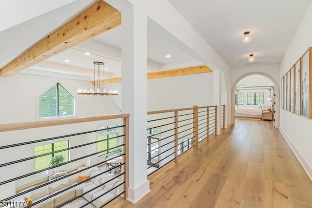 corridor with baseboards, a chandelier, beam ceiling, and wood finished floors