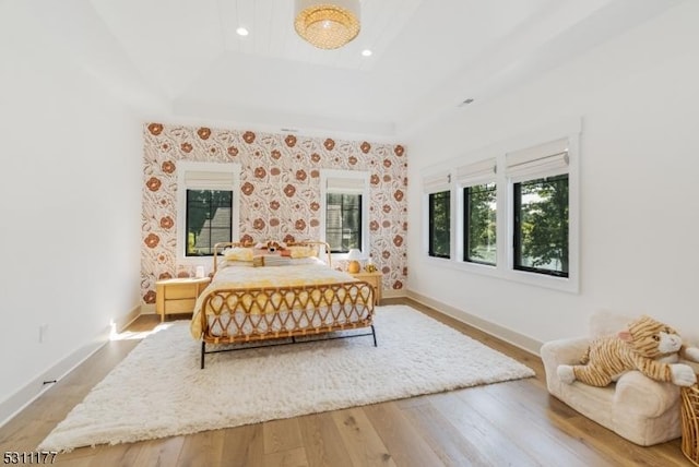 bedroom with a tray ceiling, recessed lighting, wood finished floors, and baseboards