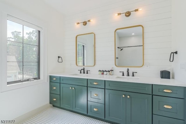 full bathroom with baseboards, double vanity, a sink, and tile patterned floors