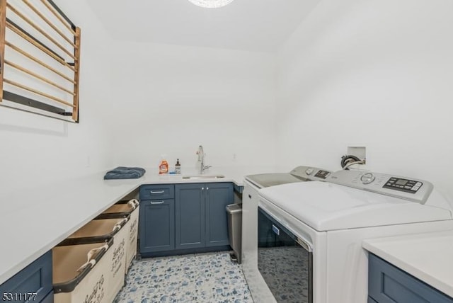 clothes washing area with cabinet space, a sink, and separate washer and dryer