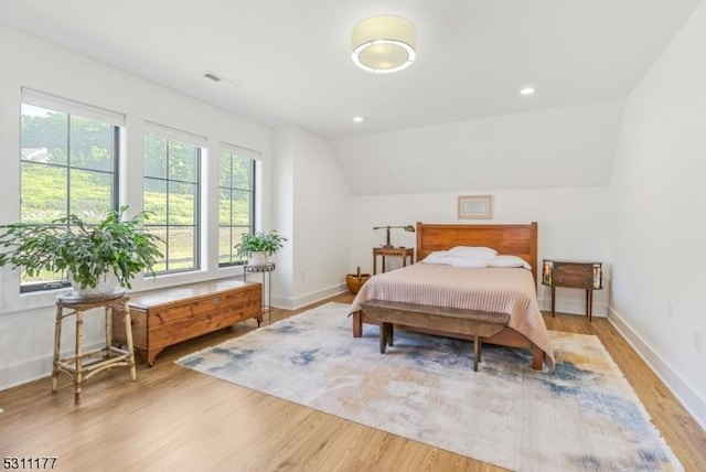 bedroom with lofted ceiling, baseboards, and wood finished floors