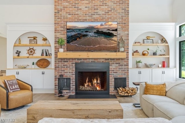 living room featuring a fireplace, wood finished floors, and built in features