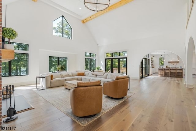 living area featuring arched walkways, hardwood / wood-style floors, a wealth of natural light, and a notable chandelier