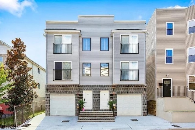 multi unit property featuring a garage, driveway, and brick siding