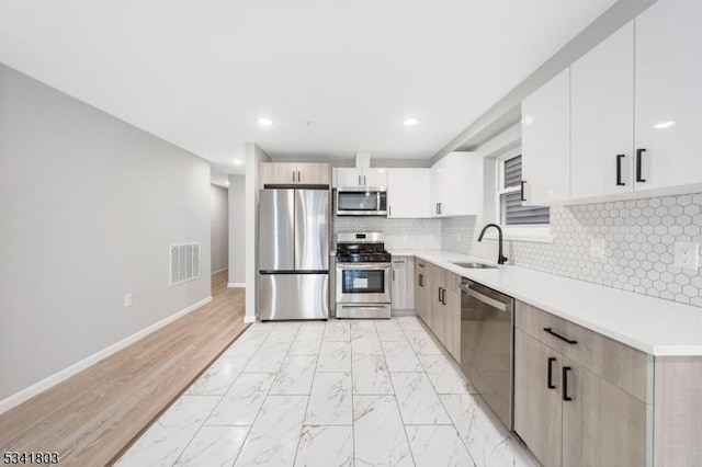 kitchen featuring baseboards, marble finish floor, appliances with stainless steel finishes, light countertops, and tasteful backsplash