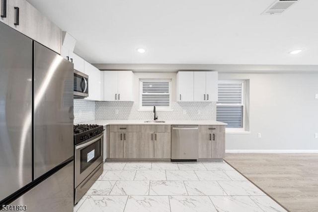 kitchen featuring visible vents, stainless steel appliances, a sink, and light countertops