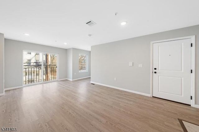 unfurnished living room with light wood-type flooring, baseboards, visible vents, and recessed lighting