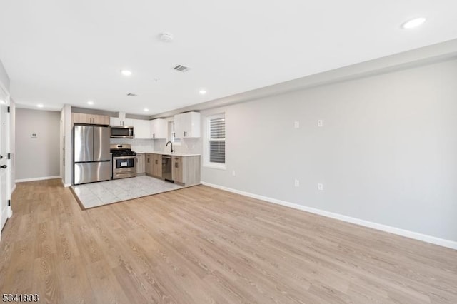 kitchen with light countertops, visible vents, light wood-style flooring, appliances with stainless steel finishes, and baseboards