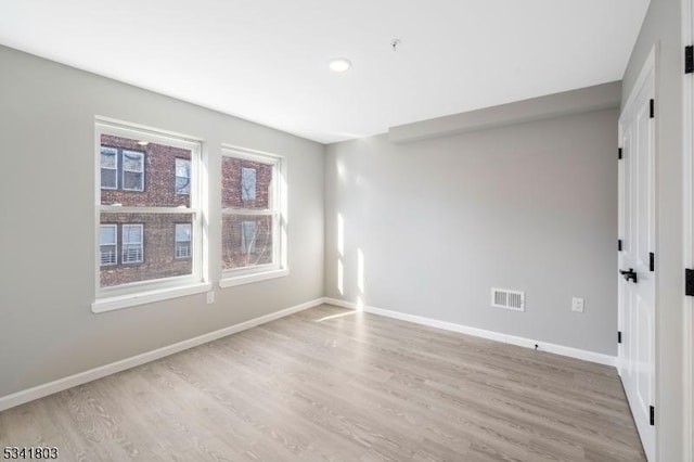 spare room featuring visible vents, baseboards, and wood finished floors