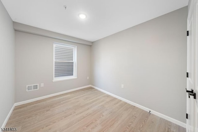 unfurnished room with light wood-type flooring, visible vents, and baseboards