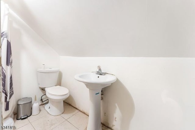 bathroom with vaulted ceiling, toilet, and tile patterned floors