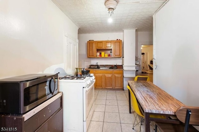 kitchen featuring light tile patterned floors, a sink, open shelves, stainless steel microwave, and white gas range