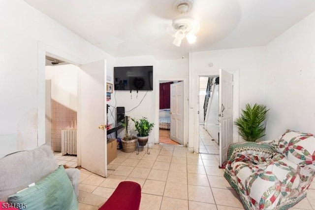 living area with light tile patterned flooring, a ceiling fan, and radiator