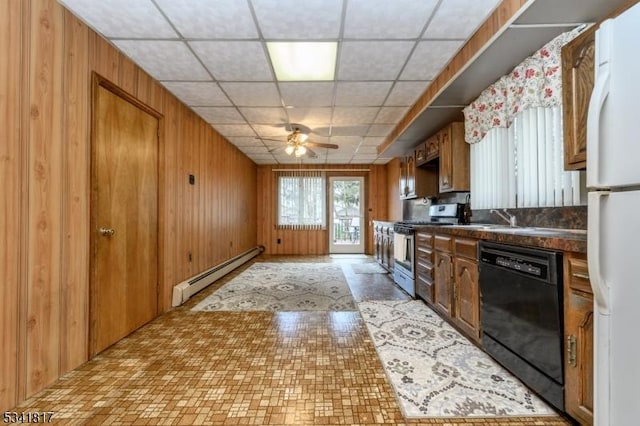 kitchen with stainless steel gas stove, black dishwasher, dark countertops, wood walls, and a baseboard heating unit