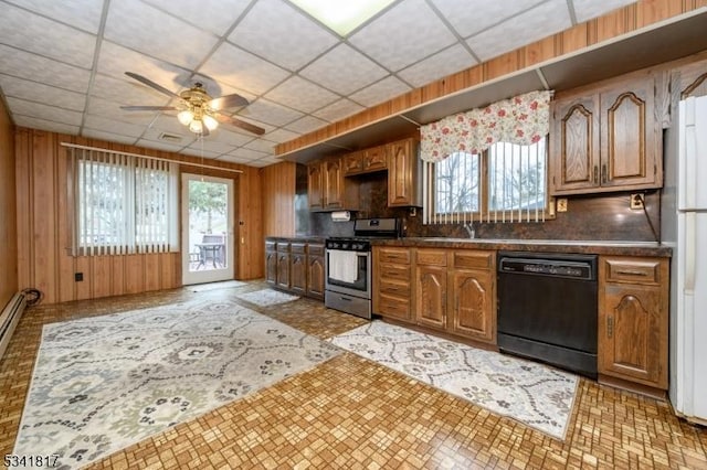 kitchen with dark countertops, black dishwasher, stainless steel range with gas stovetop, and wooden walls