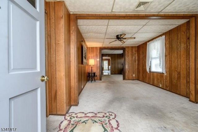 empty room with a ceiling fan, visible vents, and wooden walls