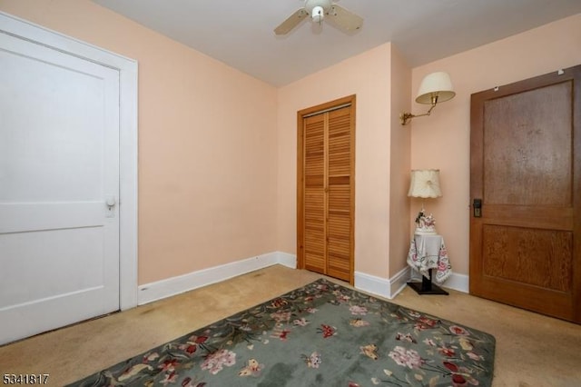 carpeted bedroom with ceiling fan, baseboards, and a closet