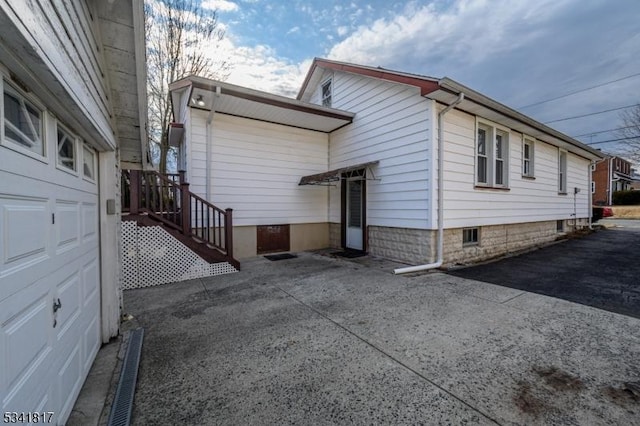 rear view of property featuring a garage and driveway