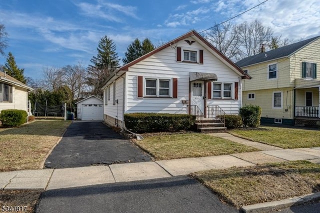 bungalow-style home with a garage, a front yard, aphalt driveway, and an outdoor structure