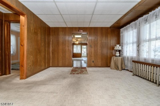 spare room featuring wooden walls and radiator