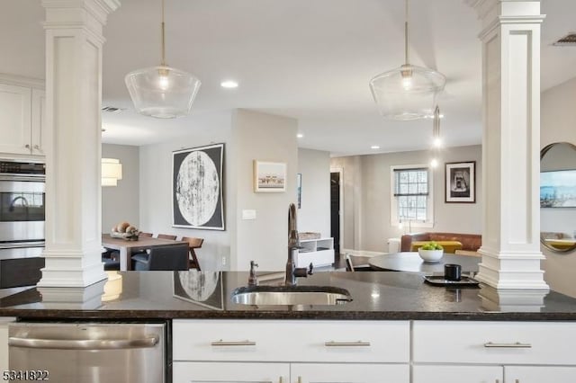 kitchen with stainless steel appliances, white cabinetry, a sink, and ornate columns